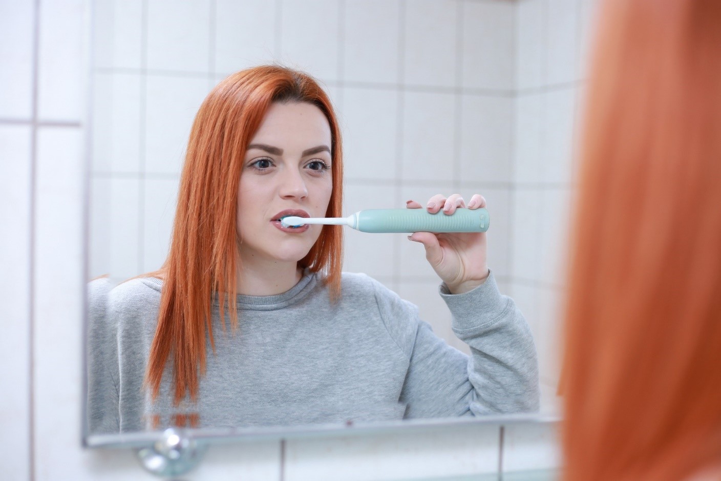 A woman brushing teeth with a smart sonic toothbrush