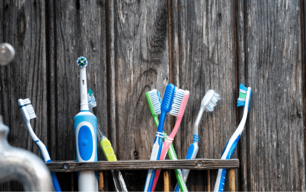 An electric toothbrush alongside traditional toothbrushes